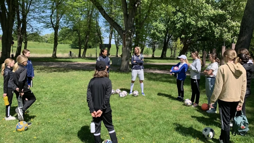 A photo of young people in sportswear in a circle, learning about FootGolf.