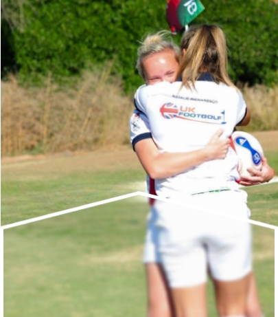 Two female footgolf players embracing on a golf course.