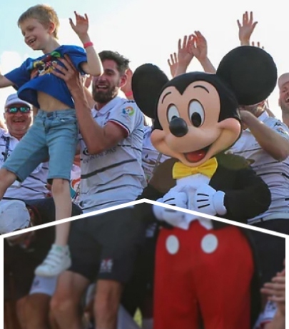 A group of people cheering next to a Mickey Mouse mascot.